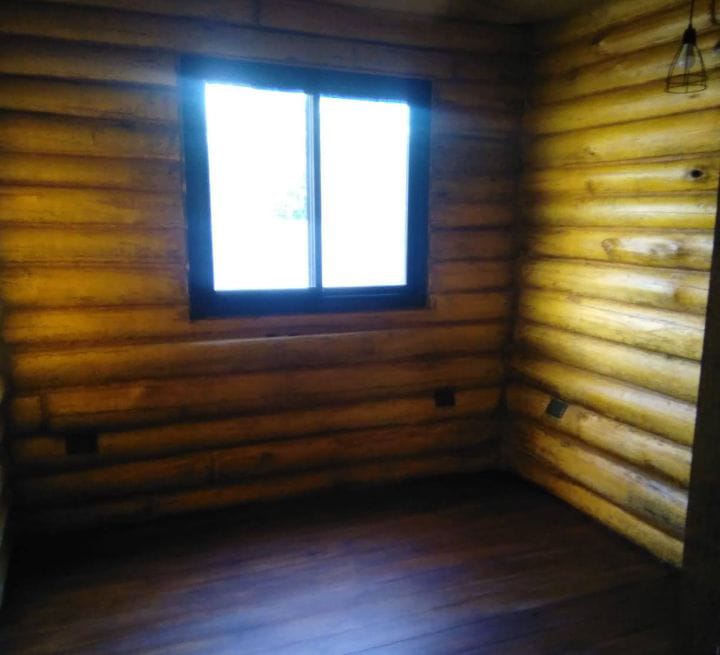 Habitacion interior con paredes de tronco y ventana