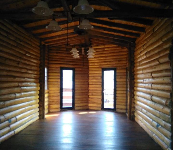Interior de cabaña de tronco - salon con puerta arqueada y pisos de madera